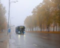 Blue urban electric bus in dense fog on an autumn day.