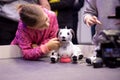 Moscow, Russia - October 04, 2019: child girl pets and plays with two Aibo Robotic pets designed and manufactured by