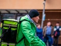 Moscow, Russia - October 19, 2019: Courier of Asian ethnicity in uniform and branded green delivery club backpacks with bike on