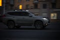 Evening traffic on the city streets. Gray Mitsubishi Pajero Sport 2020 model SUV driving in night urban road
