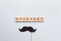 Moscow, Russia - October 07, 2019: Inscription Movember, accessory in form of black moustache on stick on grey background.