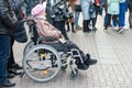 Moscow, Russia - October 19, 2019: A senior disabled woman in a wheelchair watching and listening street musicians