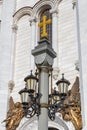 Moscow, Russia - October 03, 2019: Stone pillar with lanterns and golden cross on top against wall of Cathedral of Christ the