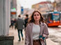 Moscow, Russia - October 19, 2019: Young woman with long hair holds smartphone in her hand and walks along the street. The phone Royalty Free Stock Photo