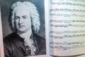 A portrait of Johann Sebastian Bach on the opened sheet music. Interior of musical room. Famous people and their works.