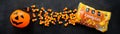 Banner with plastic pumpkin basket, candy corn Brachs spilled out of the pack. Halloween sweets. Royalty Free Stock Photo