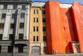 Moscow, Russia, September 2019: Old brick building is covered with an orange cloth for reconstruction and repair work. Nearby part