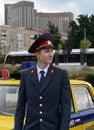 A reconstructor in the old Soviet uniform of a police officer at a car at an exhibition of old equipment
