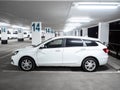 White Lada Vesta SW station wagon in an empty multi-storey car park at night.