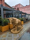 Moscow, Russia - September 22, 2021: The statue of the golden bull is installed near a cafe on the street on a rainy day. Vertical