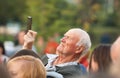 Unidentified senior man filming scene by mobile phone during a concert dedicated Moscow city day on September 9, 2019