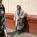 A woman with sealed eyes, pretending to be blind, with a stick in her hand, asks for alms in the street