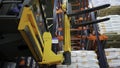 Moscow - Russia, 04.20.2022: Warehouse worker driver in uniform moving cardboard boxes by forklift stacker loader