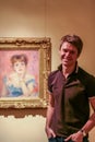 A young man standing by the picture of Renoir `Portrait of the Actress Jeanne Samary` in the art gallery of the Pushkin Museum.