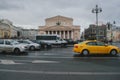 a stream of cars and yellow taxis travels fast against the backdrop of the Bolshoi Theater in Moscow