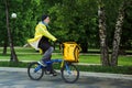 05.2020, Moscow: Tired young man delivery courier Yandex. Food rides a bicycle in a park in Moscow,