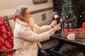 Moscow 11.29.2021. woman holding in hands sparklers bengal fire sticks sitting on chair and table with drinks outdoor on happy new