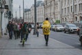 Yandex food delivery courier. Food in a yellow jacket rides a scooter along a street in Moscow