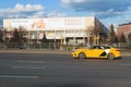 yellow Yandex taxi rides along the Crimean bridge street near the central house of the artist