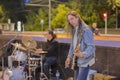 The central street of the city. Street musicians perform. A man with a guitar and a guy playing drums