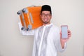 Moslem Asian man smiling happy while bring a luggage and showing blank handphone screen Royalty Free Stock Photo