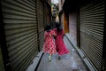 Moslem People of Egypt go shopping at Luxor Souq - two women wear bright red dresses from behind