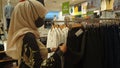 A Moslem woman is choosing clothes in a shop