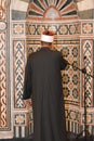 A mosque Imam preacher muezzin in front of the microphone reciting Adhan Azan or calling loudly for the prayer