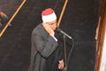 A mosque Imam preacher muezzin in front of the microphone reciting Adhan Azan or calling loudly for the prayer