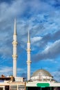 Mosque minaret, dome, loudspeakers and ridge against a vibrant cloudy blue sky background