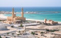 Mosque with to minarets and a small fort with ocean in background on a hot sunny day. Travel in the Musandam peninsula Royalty Free Stock Photo