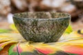 Moss Agate hand carved polished bowl in the middle of a circle made of colorful parrot feathers.