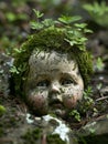 Moss-covered doll head emerging from forest floor