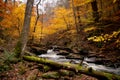 A moss covered fallen tree laying in front of cascade waterfalls surrounded by Autumn leaves