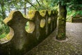 Medieval moss-covered ornamental wall and paved path in a lush, green forest in Portugal