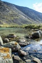 Moss-covered stones in the clear water of a turquoise lake against the backdrop of mountains Royalty Free Stock Photo