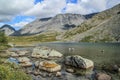 Moss-covered stones in the clear water of a turquoise lake against the backdrop of mountains Royalty Free Stock Photo