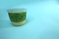 A moss pudding or pandanus pudding in a closed plastic cup, taken from the side view.