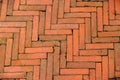 Mossy diagonal pattern of brick pavement in a herringbone style for background, Old orange bricks tiled floor with zigzag pattern. Royalty Free Stock Photo