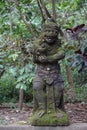 Mossy statue in Bali Indonesia with jungle and palm trees in the back