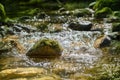 Mossy stone in a rushing mountain stream Royalty Free Stock Photo