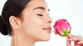 The most amazing fragrance. Studio portrait of an attractive young woman smelling a pink rose against a light background