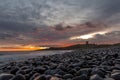 The most beautiful sunrise at Dunstanburgh Castle with the famous slippery black boulders in Northumberland, as the sky erupted wi Royalty Free Stock Photo