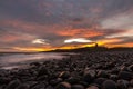 The most beautiful sunrise at Dunstanburgh Castle with the famous slippery black boulders in Northumberland, as the sky erupted wi Royalty Free Stock Photo