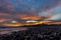 The most beautiful sunrise at Dunstanburgh Castle with the famous slippery black boulders in Northumberland, as the sky erupted wi Royalty Free Stock Photo