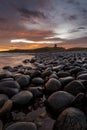 The most beautiful sunrise at Dunstanburgh Castle with the famous slippery black boulders in Northumberland, as the sky erupted wi Royalty Free Stock Photo