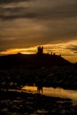 The most beautiful sunrise at Dunstanburgh Castle with the famous slippery black boulders in Northumberland, as the sky erupted wi Royalty Free Stock Photo