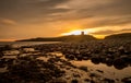 The most beautiful sunrise at Dunstanburgh Castle with the famous slippery black boulders in Northumberland, as the sky erupted wi Royalty Free Stock Photo