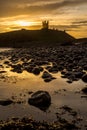 The most beautiful sunrise at Dunstanburgh Castle with the famous slippery black boulders in Northumberland, as the sky erupted wi Royalty Free Stock Photo
