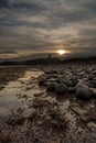 The most beautiful sunrise at Dunstanburgh Castle with the famous slippery black boulders in Northumberland, as the sky erupted wi Royalty Free Stock Photo